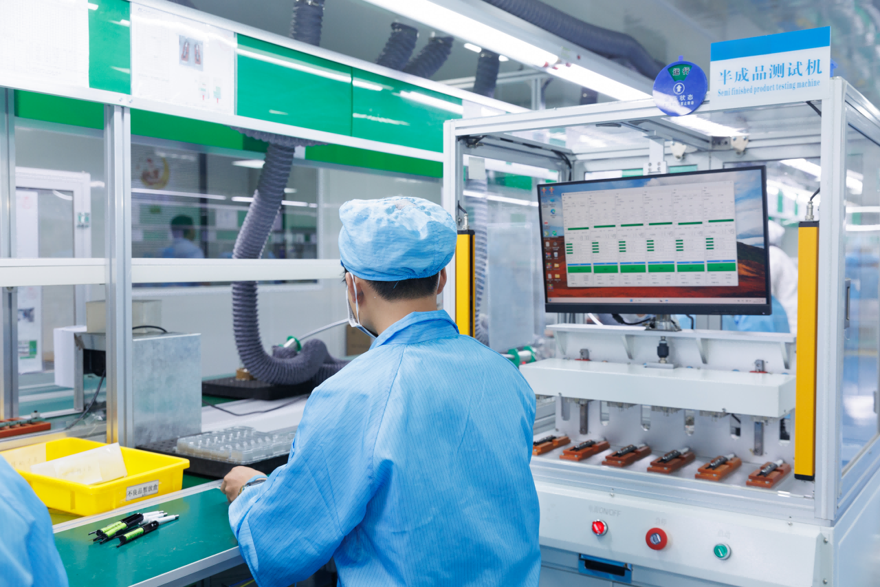 A quality control inspector examining an electric toothbrush on the production line