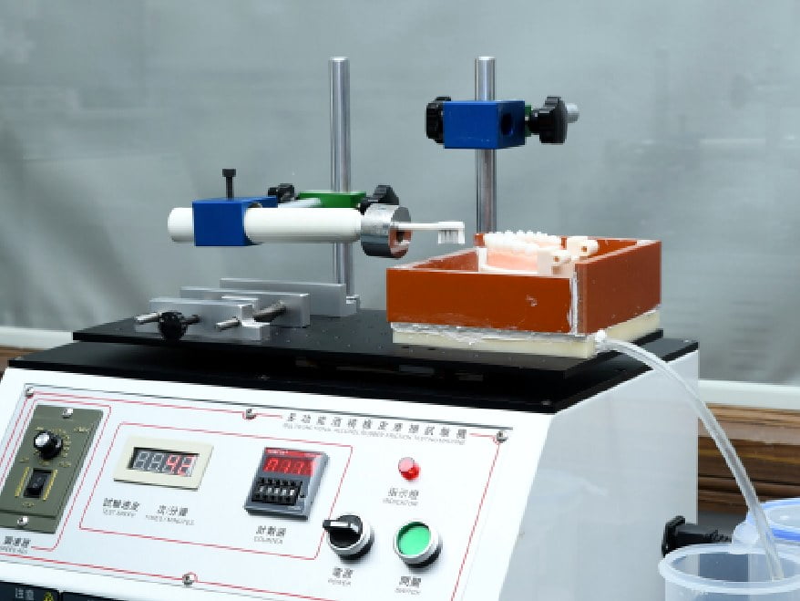 Automated brush-head life testing machine cycling a brush head
