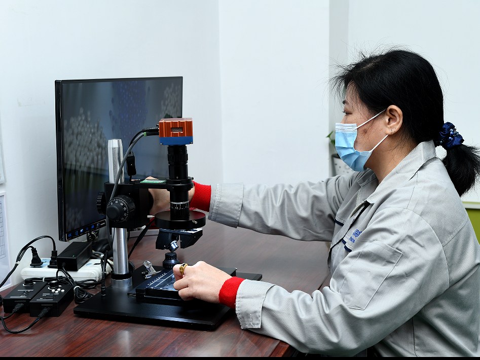 Engineer examining a component under a video measuring microscope with magnified display