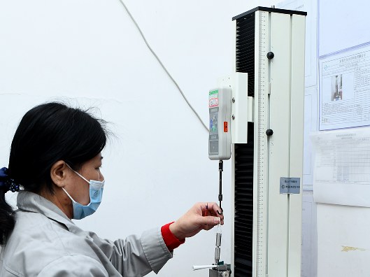 Technician operating a vertical force tester and recording results