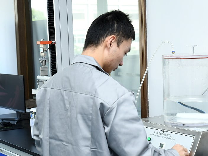 Technician operating an automatic vacuum sealing performance tester with a submerged sample